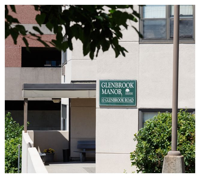 The Glenbrook Manor sign sits on the side of the concrete building next to the wheelchair-accessible, covered entrance.
