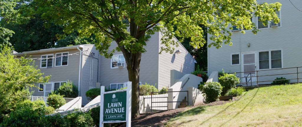 The Lawn Avenue sign sits under a large tree behind the well-maintained townhouses.
