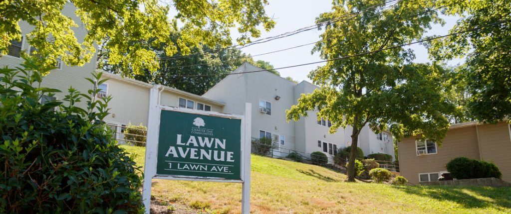 The Lawn Avenue sign sits in a large grassy area surrounded by the buildings; it reads Lawn Avenue, 1 Lawn Ave.