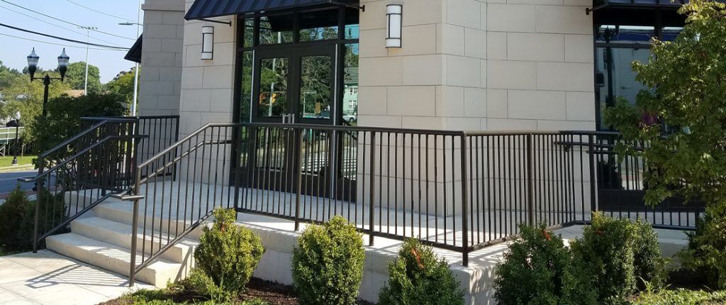 The contemporary entrance to Park 215 features stairs as well as a wheelchair accessible ramp punctuated by shrubbery.