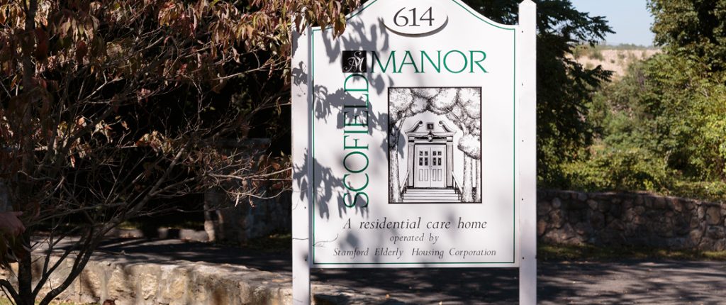 The Scofield Manor sign reads 614 Scofield Manor, a residential care home operated by Stamford Elderly Housing Corporation.