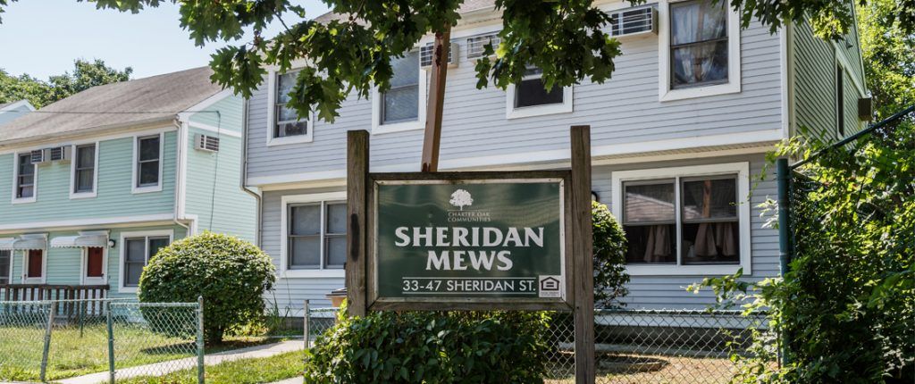 The wooden sign for Sheridan Mews features the Equal Housing Opportunity logo and reads Sheridan Mews, 33–47 Sheridan St.