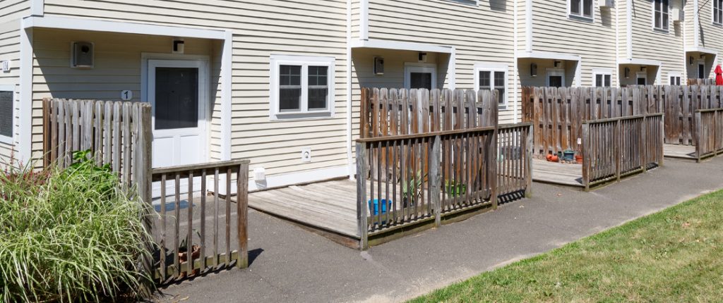 The entrances are equipped with short overhangs, porch lights, windows, and fenced, semi-private decks.